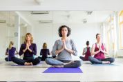 Drei Frauen sitzen im Sportstudio auf Yogamatten im Meditationssitz autogenes-training
